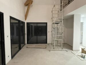 Photo d'un salon en travaux avec de grandes baies vitrées en aluminium, un espace vide et en longueur.